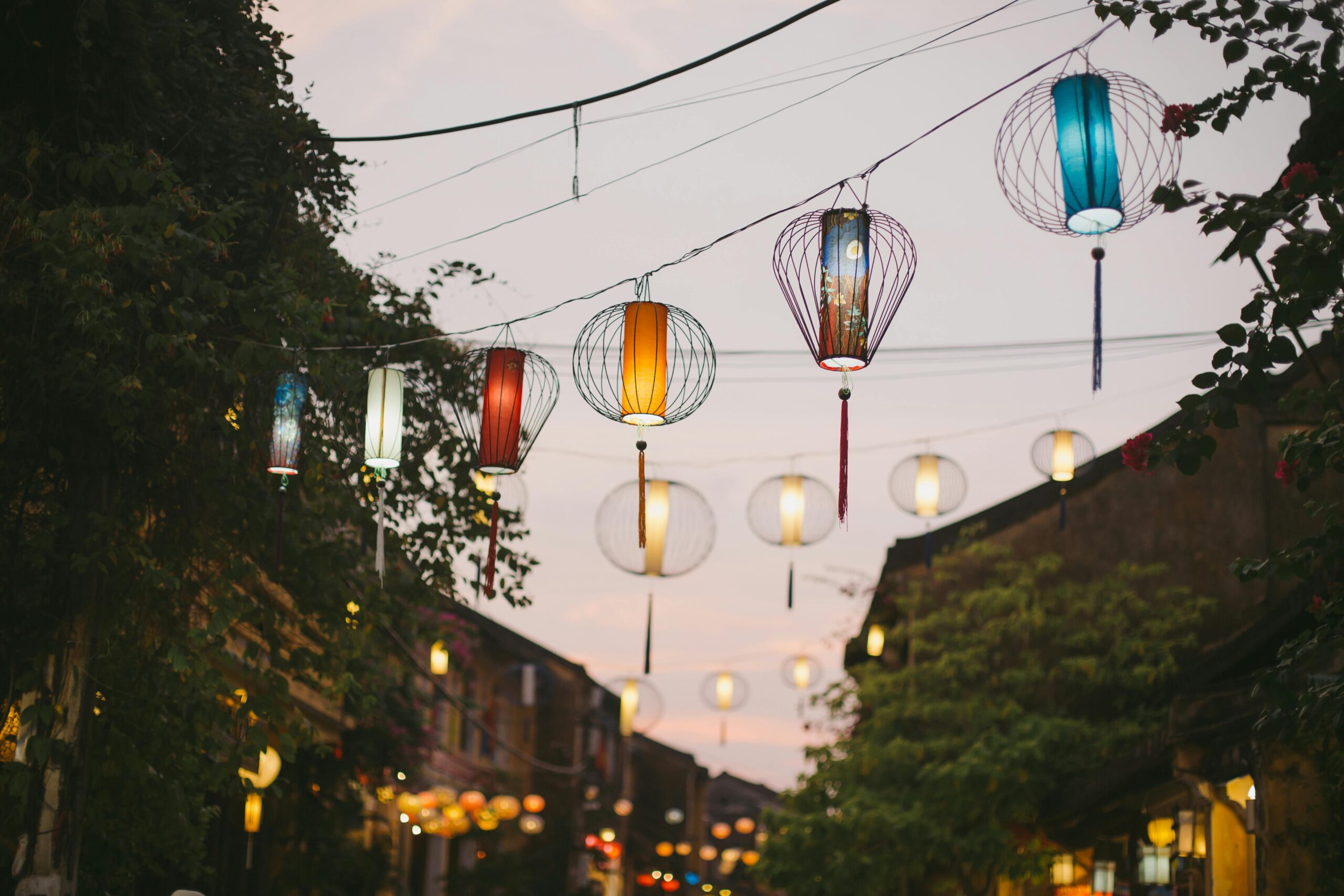 Charming evening street with vibrant lanterns against a dusk sky.